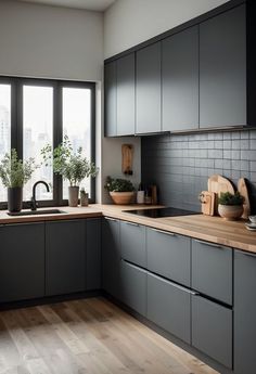 a kitchen with black cabinets and wooden counter tops, potted plants on the window sill