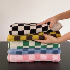 a person is stacking towels on top of each other in different colors and patterns