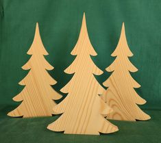 three wooden christmas trees on a green background