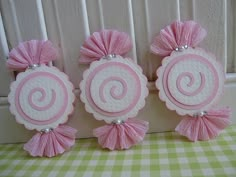 three pink and white paper decorations on a table