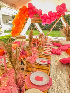 a table set up for a party with pink and orange decorations