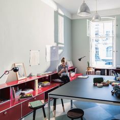 a person sitting on a chair in a room with bookshelves and desks