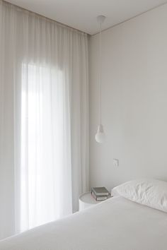 a bedroom with white walls and curtains on the windowsill