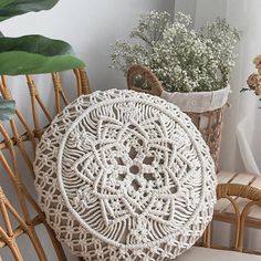 a white crocheted doily sitting on top of a chair next to a potted plant