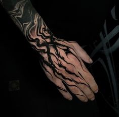 a man's hand with black and white ink on it, holding a cross