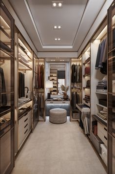 a walk - in closet with lots of clothes on shelves and drawers, along with a foot stool