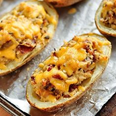 baked potato skins with cheese and bacon on top, sitting on aluminum foil in a baking pan