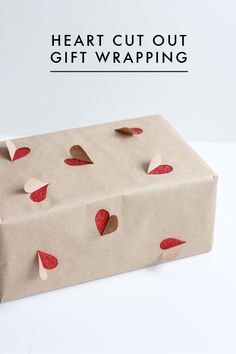 a gift wrapped in brown paper with red hearts on it and the words, heart cut out gift wrapping