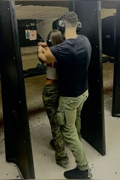 a man and woman are aiming at an object in the target range with headphones on