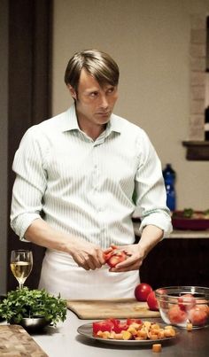 a man standing in front of a cutting board with tomatoes on it