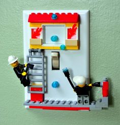 a lego light switch plate with two people on it and one is holding a ladder