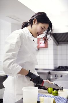 a woman in a kitchen cutting apples on a cutting board