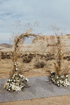 an outdoor ceremony setup with flowers and greenery on the ground in front of a desert landscape