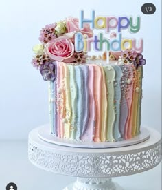 a multicolored birthday cake sitting on top of a white pedestal