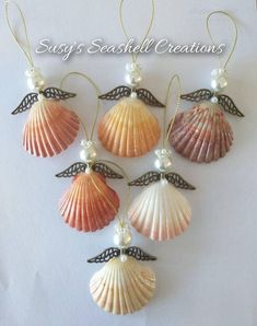 six seashells are hanging on a white background with pearls and beads in the shape of angel wings