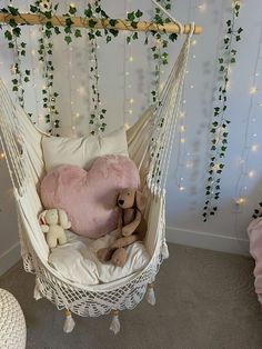 a white hammock with pink pillows and teddy bears on it in a bedroom