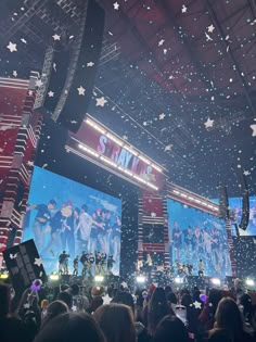 the stage is lit up with stars and confetti as people are standing in front of them