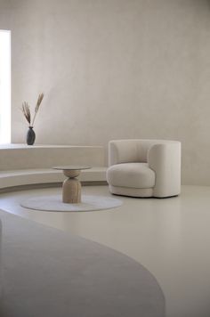 a living room with a white couch and chair next to a round coffee table in front of a window