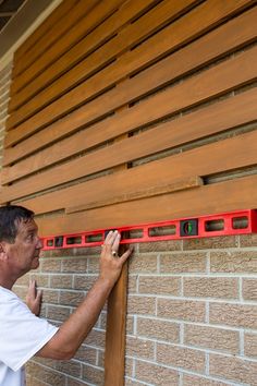 a man measuring the width of a wooden wall