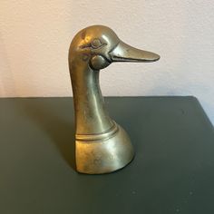 a metal duck head sitting on top of a black table next to a white wall