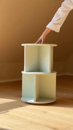 a person reaching for something on top of a small shelf in the middle of a room