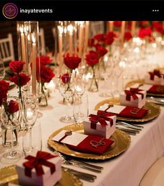 the table is set with red roses and silverware