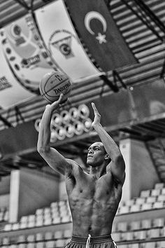 a shirtless man holding a basketball up in the air