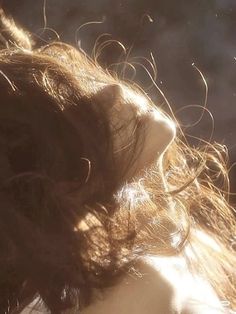 the back of a woman's head with her hair blowing in the wind on a sunny day