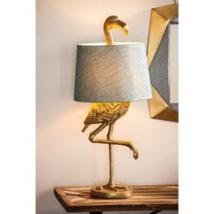 a lamp that has a gold bird on it and a blue shade is sitting on top of a wooden table