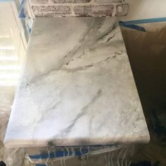 a white marble counter top being installed in a room with blue tape around it and some bricks on the wall