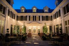 an outside view of a large white building with lights on it's front entrance