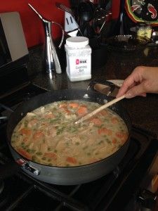 a person stirring chicken pot pie filling in a skillet