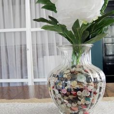 a vase filled with buttons and flowers on top of a table