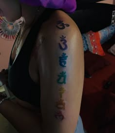 a woman with chinese writing on her arm and chest is wearing a purple hat in the background