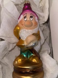 a glass ornament with a gnome holding something in it's hand and wearing a purple hat