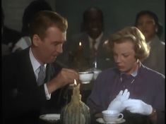 a man and woman sitting at a table in front of a teapot with a candle on it