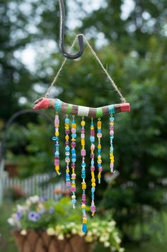 a wind chime hanging from a tree branch with beads on it's end