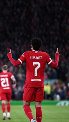 a soccer player with his hands in the air and one hand out, walking on a field