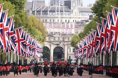 many british flags are flying in the air as people ride bikes down a city street