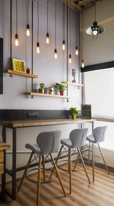 three stools are sitting at the bar with lights hanging from the ceiling above them