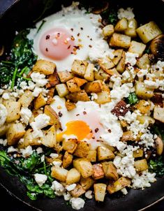 an egg is on top of potatoes in a skillet with spinach and feta cheese