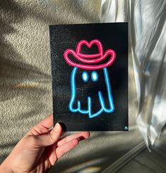 a person holding up a neon sign with an elephant wearing a hat