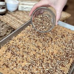 a person is sprinkling seeds into a cookie sheet