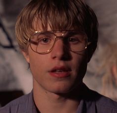 a young man wearing glasses looking at the camera