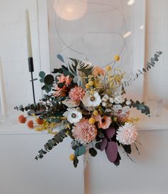 a bouquet of flowers sitting on top of a white table next to a candle holder