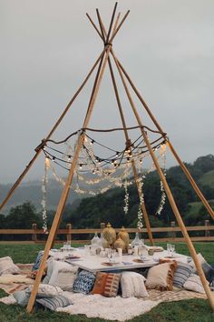 a teepee is set up with pillows and lights for a picnic or dinner party