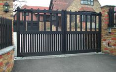 a black gate with brick walls and an iron fence on the side of a house