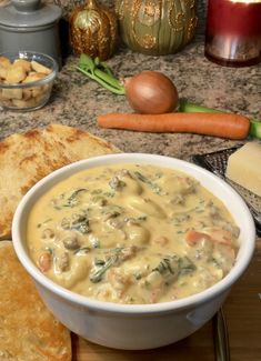 a white bowl filled with soup next to some bread and other food on a table