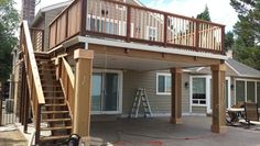 a deck with stairs leading up to the second floor and an attached balcony above it