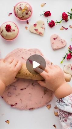 a child is rolling out pink frosted cupcakes on top of a white table